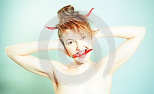 Funny girl portrait as a devil with the red chili peppers horns