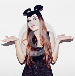 Funny girl represents a small cat or mouse. Woman with a bright makeup hairstyle and night dress mouse ears having fun. On white