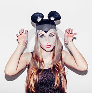 Funny girl represents a small cat or mouse. Woman with a bright makeup hairstyle and night dress mouse ears having fun. On white