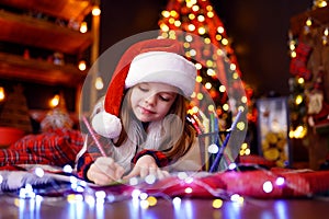 Funny girl in Santa hat writes letter to Santa