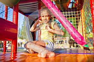 Funny girl sits on a colored mat in entertainment center with colorful equipmen