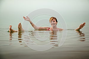 Funny girl swims in water of Dead Sea in Jordan and fog