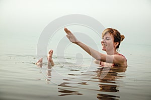 Funny girl swims in water of Dead Sea in Jordan and fog