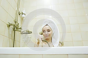 Funny girl in towel, relaxing in bathtub