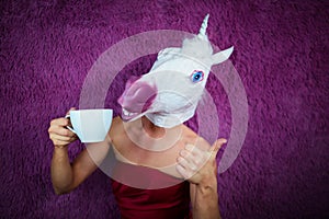 Funny girl unicorn drinks tea and shows thumbs up gesture