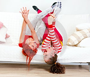 Funny girlfriends in playful mood lying on sofa