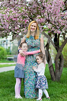 Funny girls walking on the lawn with her mother. Sisters play together with mom. maternal care. happy family