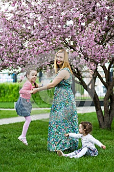 Funny girls walking on the lawn with her mother. Sisters play together with mom. maternal care. happy family