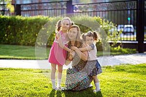 Funny girls walking on the lawn with her mother. Sisters play together with mom. maternal care. happy family