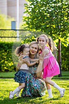 Funny girls walking on the lawn with her mother. Sisters play together with mom. maternal care. happy family