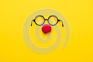 Funny glasses, red clown nose and tie lie on a colored background, like a face