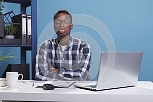 Funny and goofy office working person making amusing playful face while sticking out tongue.