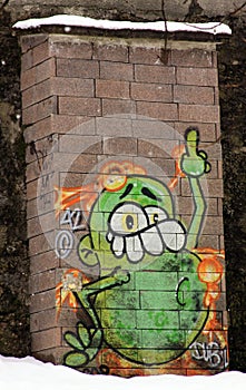 Funny green cartoon graffiti showing the finger, on brick wall in Salzburg