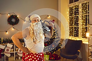 Funny granddad with Santa beard, headphones and boombox having fun on Christmas night at home