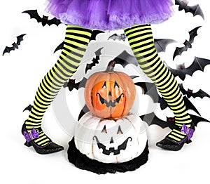 Funny green black Striped legs of a little girl with halloween costume of a witch with witch shoes and smiley halloween pumpkin