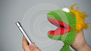 Funny green puppet browsing in smartphone