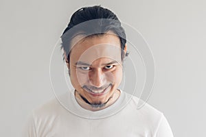 Funny grinning smile face of man in white t-shirt and grey background.