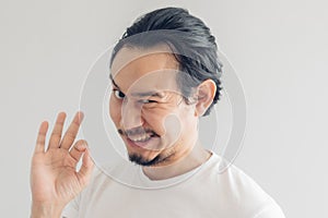 Funny grinning smile face of man in white t-shirt and grey background.