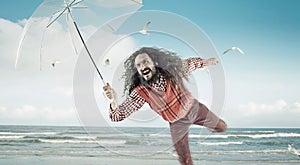 Funny guy holding an umbrella on a beach