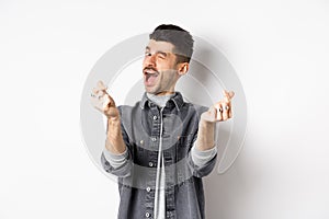 Funny guy winking and showing hand hearts sign, feeling romantic and happy, standing on white background