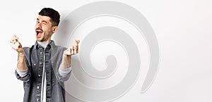 Funny guy winking and showing hand hearts sign, feeling romantic and happy, standing on white background