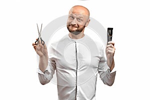 Funny hairdresser man. A bald European man hairdresser with a beard holding scissors and an electric razor with a funny