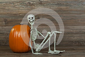 Funny Halloween skeleton sitting with pumpkin