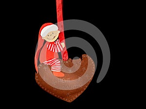Funny handicraft of a small child sitting on a gingerbread heart made of paper by a child
