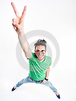 Funny handsome man with hipster glasses showing victory and smiling - wide angle