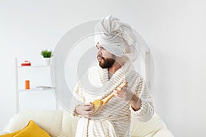 Funny handsome man pretends to play on massage brush as a guitar. Fun, spa and humor concept.