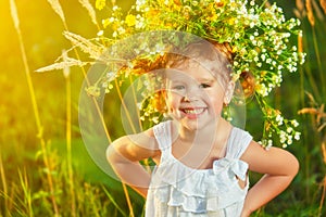 funny happy baby child girl in a wreath on nature laughing in summer