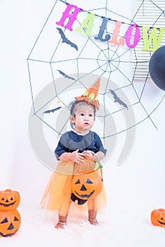 Funny happy baby girl in Halloween costume with pumpkin Jack