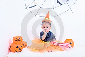 Funny happy baby girl in Halloween costume with pumpkin Jack