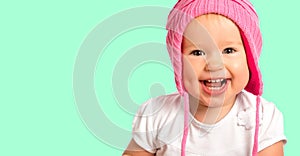 Funny happy baby girl in a pink winter knitted hat laughing