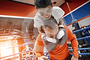 Funny happy boy in boxing gloves holding his dad`s neck