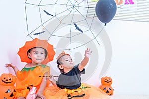 Funny happy brethren baby girl and kid boy in Halloween costume with pumpkin Jack