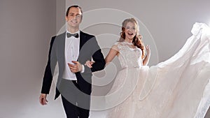 Funny and happy bride and groom, dance and jump with happiness, married. Studio portrait, light background