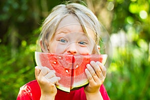 Funny happy child eating watermelon outdoors
