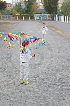 Funny and happy children play in a kite. They are dressed in white sweatshirts and pants. Running on the sunset