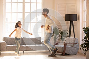 Funny happy dad and kid daughter jumping dancing at home