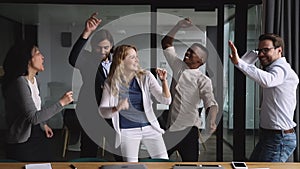 Funny happy diverse business team dancing together at corporate party