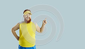 Funny happy fat man having gym workout, smiling and pointing to copy space background