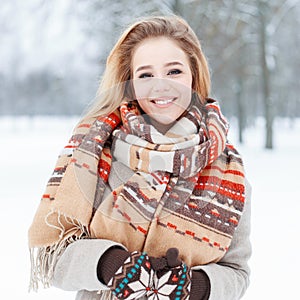 Funny happy young woman with beautiful smile in winter stylish clothes on the background of a snowy trees in the park. Cute girl.