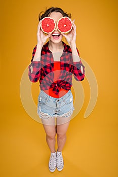 Funny happy young woman with halves of grapefruit over eyes