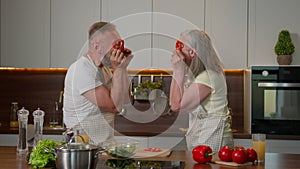 Funny hilarious Caucasian couple old happy retired family woman man having fun grimacing together make red paprika