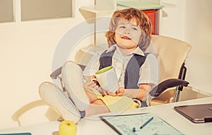 Funny homeschooling for kids. Little boss in the office, businessman. Male child playing business, holding a cup in his