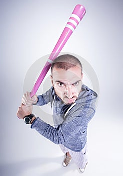 Funny hooligan with a pink baseball bat looking angry in the studio photo
