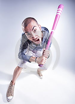 Funny hooligan with a pink baseball bat screaming in the studio