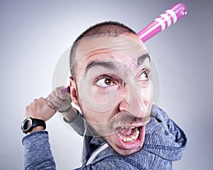 Funny hooligan with a pink baseball bat screaming in the studio photo