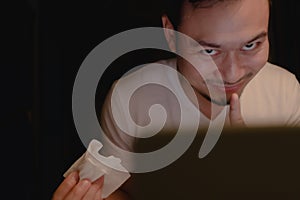 Funny horny face of man watching porn at night.